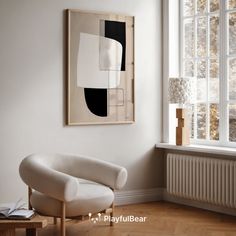 a white chair sitting in front of a window next to a painting on the wall