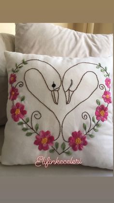 two swans making a heart with flowers on a pillow