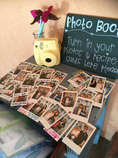 a table topped with lots of photos and a camera next to a chalkboard sign