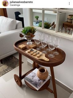 a wooden table with wine glasses and utensils on it in front of a window