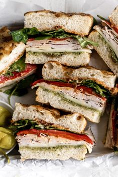 a pile of sandwiches sitting on top of a white plate next to some pickles