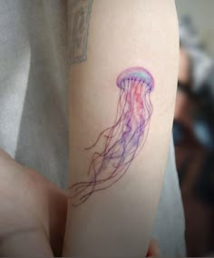 a person with a tattoo on their arm that has a purple jellyfish in it