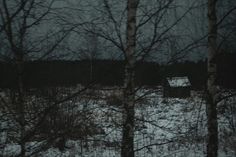 an old house in the middle of a snowy field with trees and snow covered ground