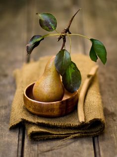 two pears in a wooden bowl with green leaves