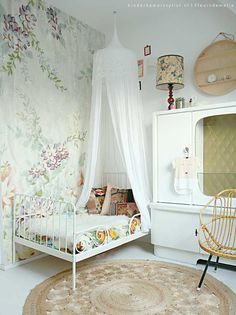 a white bed sitting in a bedroom next to a dresser and chair on top of a rug