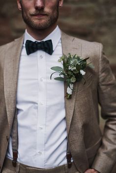 a man wearing a suit and bow tie with a boutonniere on his lapel