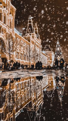 an image of christmas lights in the city with snow on the ground and buildings reflected in the water