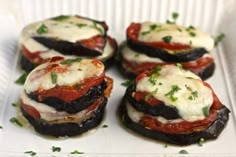 several small sandwiches with cheese and tomatoes on them sitting in a white tray, ready to be eaten