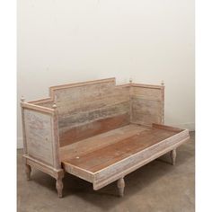 an old wooden bed frame sitting on top of a cement floor next to a white wall