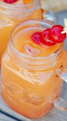 two mason jars filled with lemonade and cherries on top of a wooden table