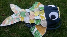 a fish made out of fabric sitting on the grass with it's eyes open