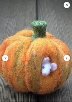 an orange felt pumpkin with a small white mouse in it