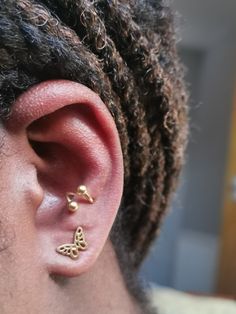 a close up of a persons ear with two small gold butterfly studs on it