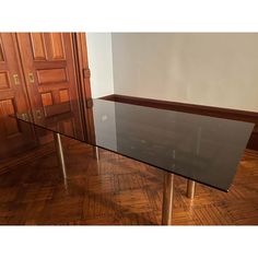 a glass table sitting on top of a hard wood floor next to a wooden door