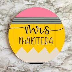 a round magnet with the words mrs mantera written in black ink on it