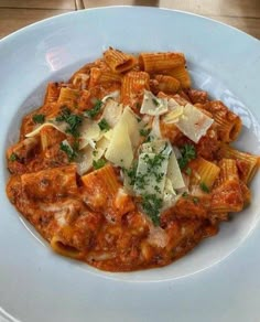 a white plate topped with pasta covered in sauce and parmesan cheese on top