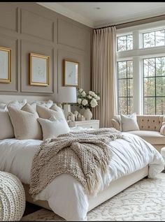 a large white bed sitting in a bedroom next to a window filled with lots of windows