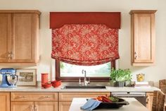 a kitchen with an orange roman blind in the window and some fruit on the counter