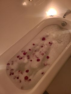 a bathtub filled with lots of foam and red berries on the inside of it