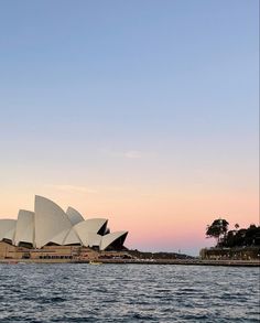 the sydney opera house is lit up at sunset