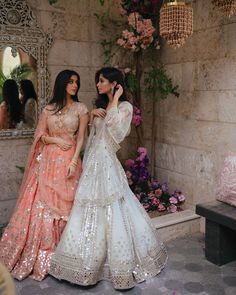 two women standing next to each other wearing dresses and holding hands in front of their faces