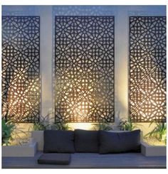 an outdoor seating area with decorative screens on the wall and potted plants next to it