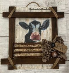 a wooden frame with a cow's face painted on it and a burlwood bow