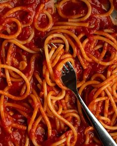 a fork is stuck into some spaghetti in a pan with sauce on it and another fork sticking out of the top