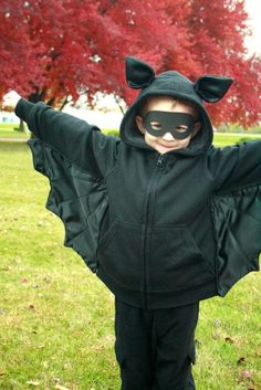 a child wearing a black cat costume with his arms spread out in the air and eyes closed