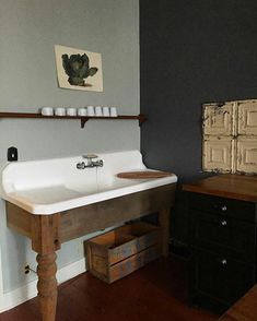 a white sink sitting on top of a wooden table next to a wall mounted painting