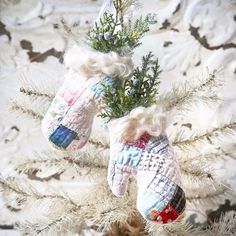 two knitted mittens hanging from a christmas tree ornament on a branch