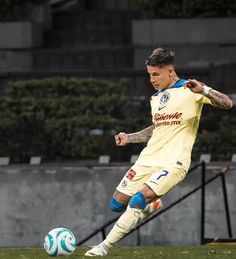 a man kicking a soccer ball on top of a field