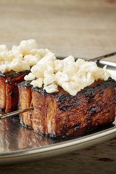 two pieces of meat sitting on top of a silver plate