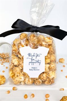 a bag filled with popcorn sitting on top of a white table next to a glass jar