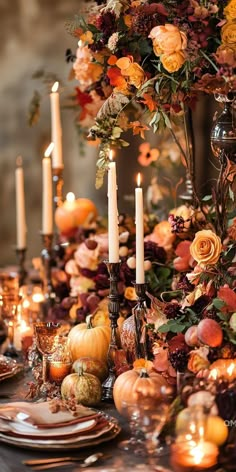 a table topped with lots of candles and plates covered in fall flowers, leaves and pumpkins