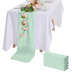 the table is set with plates and napkins, flowers on each placemat, and green runneres