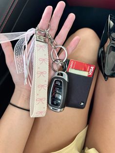 a woman's hand holding a car key chain with a cell phone attached to it