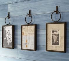 three framed pictures hanging on the wall with metal rings attached to each one's sides