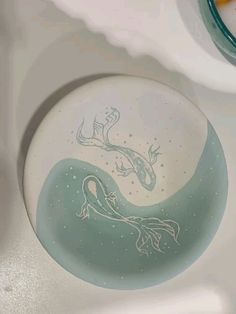 a white sink with a blue and green design on the bowl next to a faucet