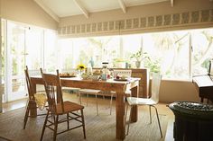 a dining room table and chairs with sun shining through the windows in front of them