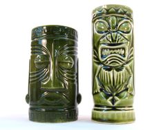 two green vases sitting next to each other on a white surface with an owl design