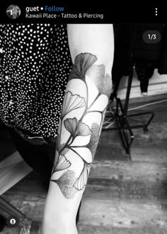 black and white photo of a woman's leg with flower tattoo on her arm