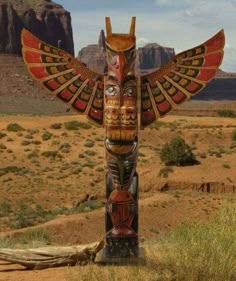 a totem pole in the desert with mountains in the background