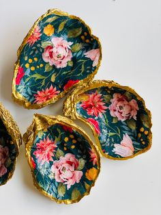 four pieces of gold foil with flowers painted on them sitting next to each other in front of a white background