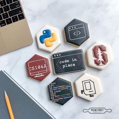 some cookies that are on top of a table next to a laptop and pencils