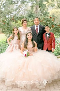 a group of people standing next to each other in front of trees and bushes with flowers