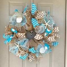 a wreath is hanging on the front door with shells, starfish and seashells