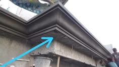 two men working on the roof of a building with blue arrows pointing up at it