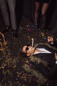 a woman laying on the ground with a toothbrush in her mouth and confetti all around her