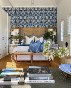 a bed room with a neatly made bed and lots of books on the table next to it